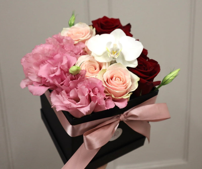 caja de rosas con lisianthus y orquidea